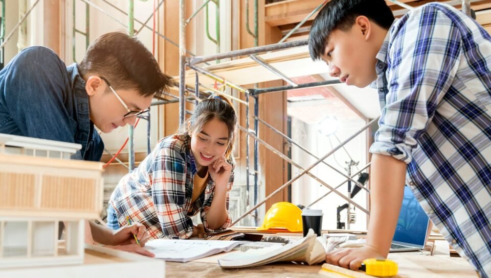 group of smart asian architect interior design team consulting with constrction engineer work brainstrom  meeting with house project blueprint and home mockup in house renovation structure background