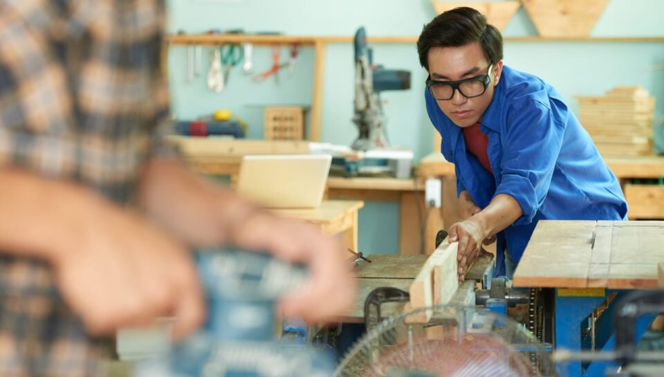 Vietnamese carpenter securing wooden plank on workbench